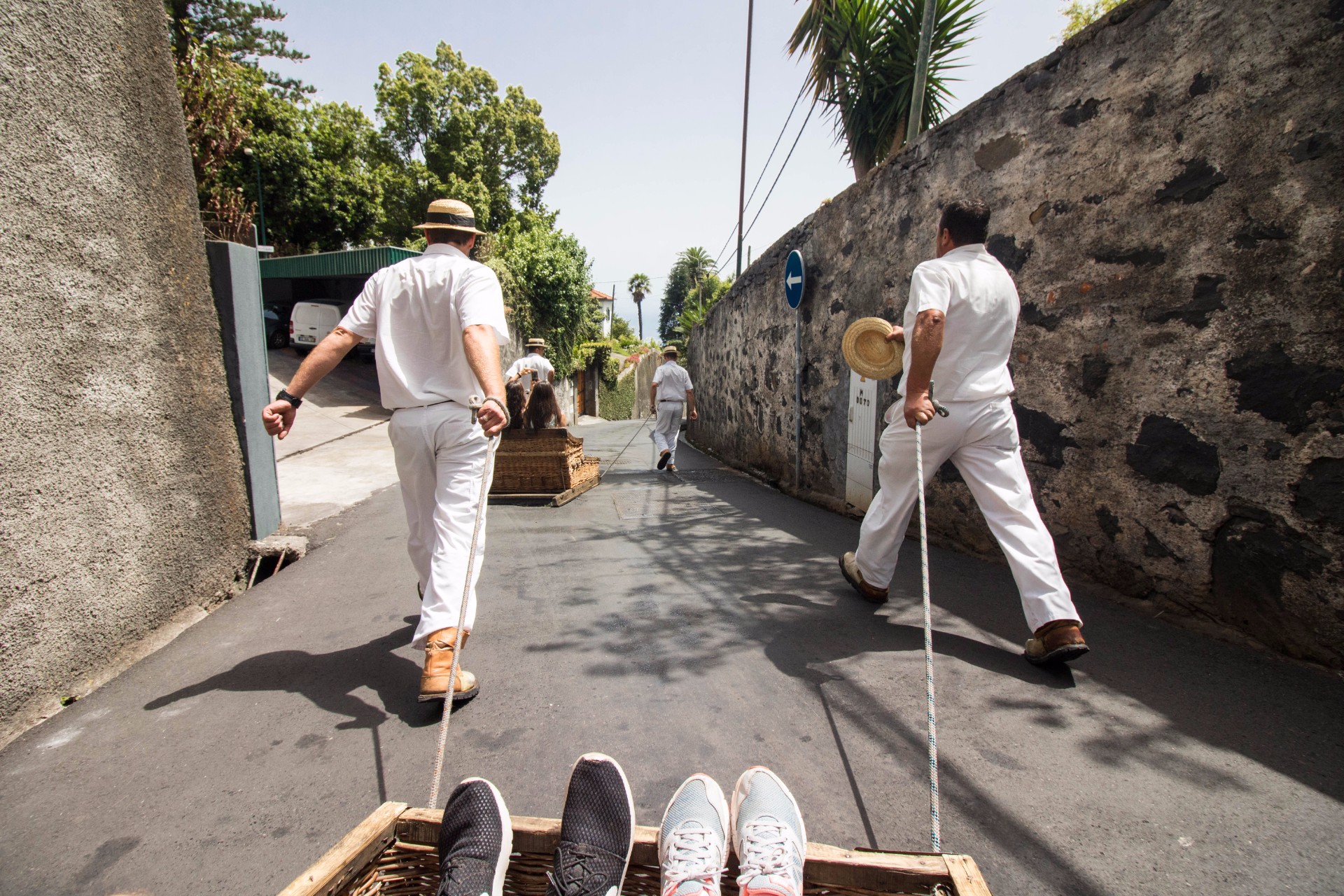 two-men-in-white-clothing-dragging-a-wicker-toboggan-sled-ride-from-monte-to-funchal