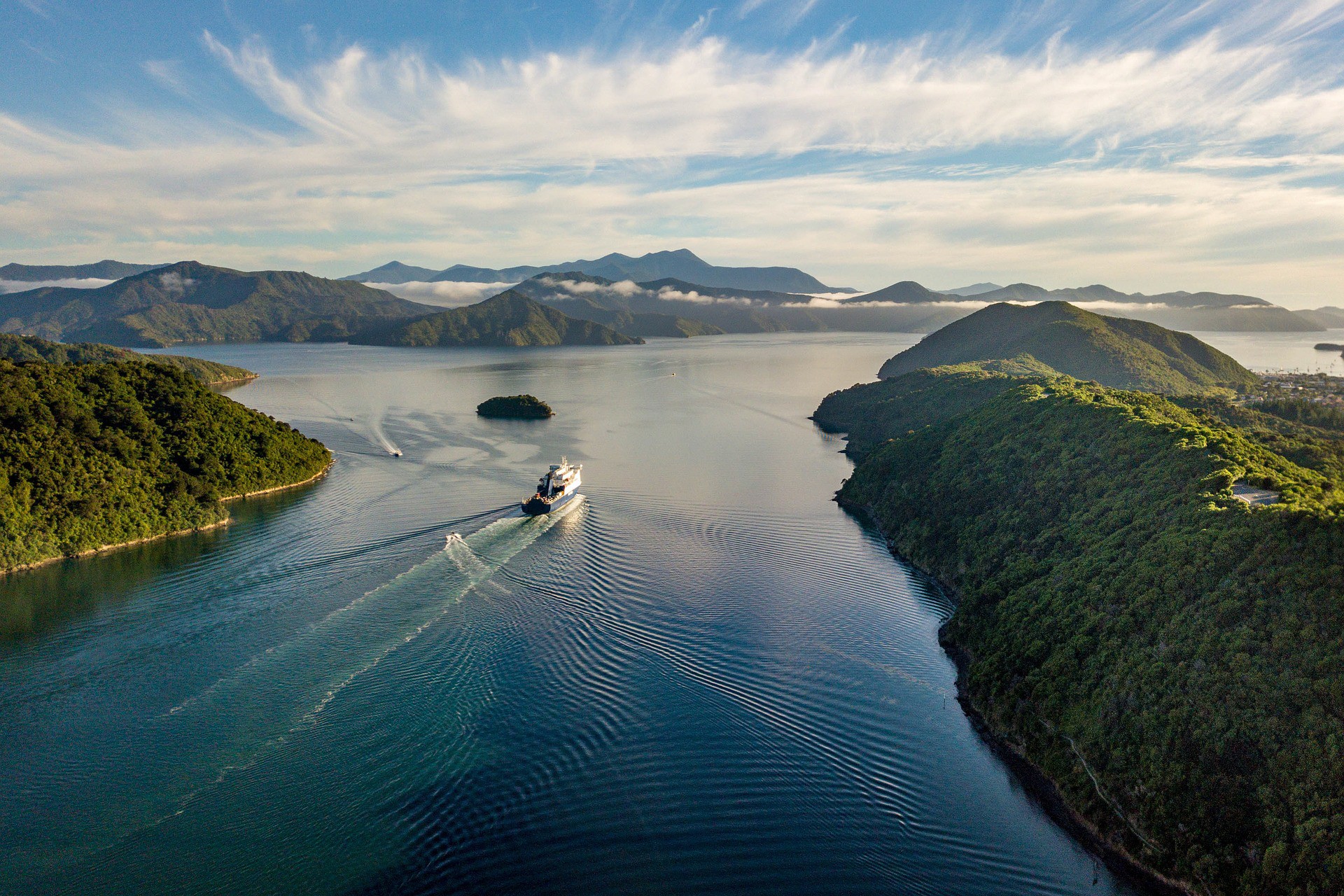 ferry-travelling-through-the-sea-beside-beautiful-green-mountains-crossing-the-cook-strait-at-sunset-new-zealand-bucket-list
