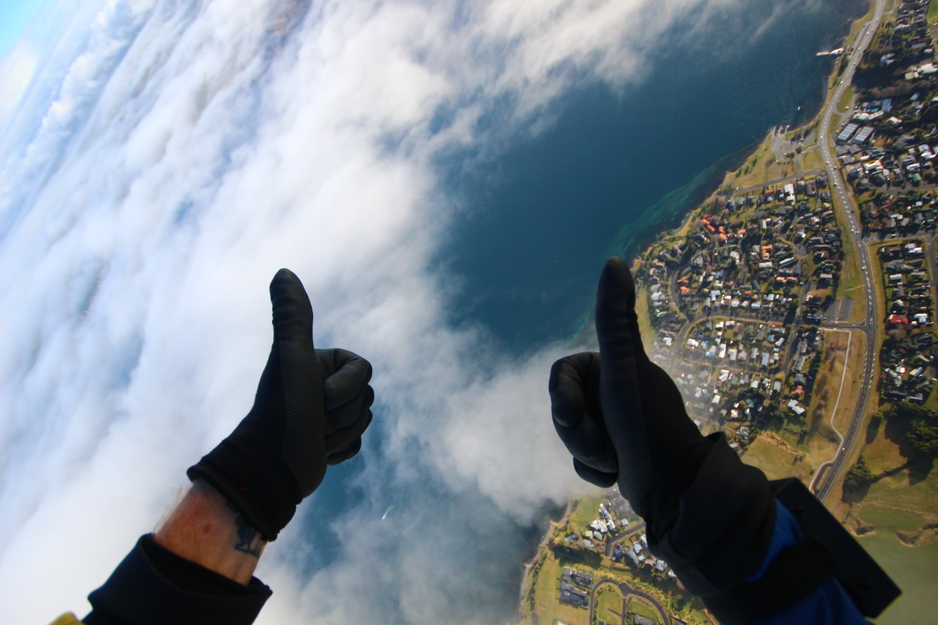 Thumbs up with gloves town below green fields blue lake clouds Skydive Taupo The Best Skydiving in New Zealand