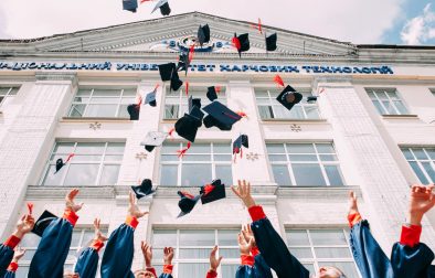 Graduation graduating university graduates throwing their hats in the air in front of a white building How to Get Into Marketing with an English Degree