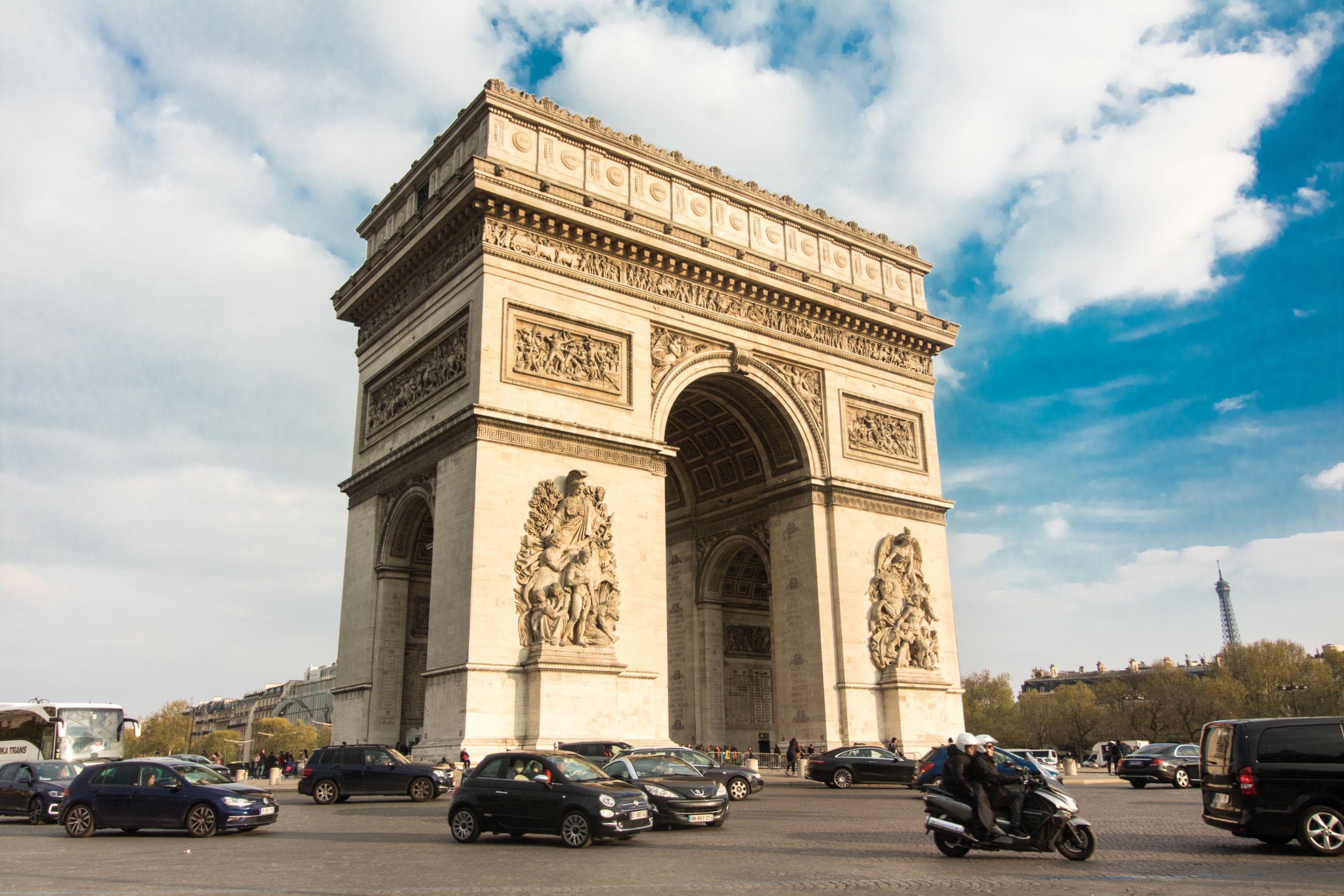 Arc de Triomphe. Cars driving in front of a famous arc and landmark in Paris on a sunny evening at golden hour.