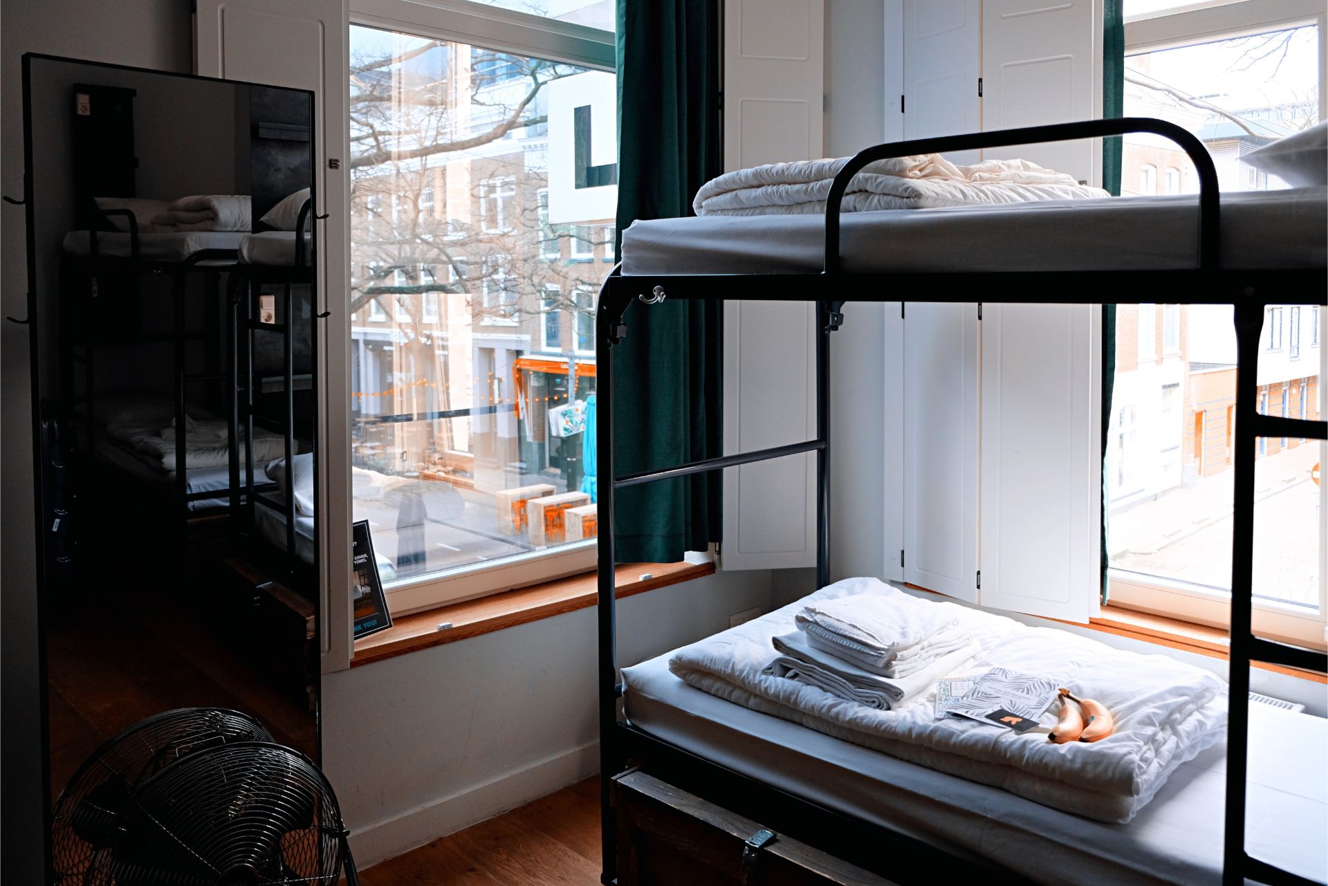 bunk-beds-with-white-linen-and-towels-in-a-hostel-room-in-a-city-sustainable-travel-tips