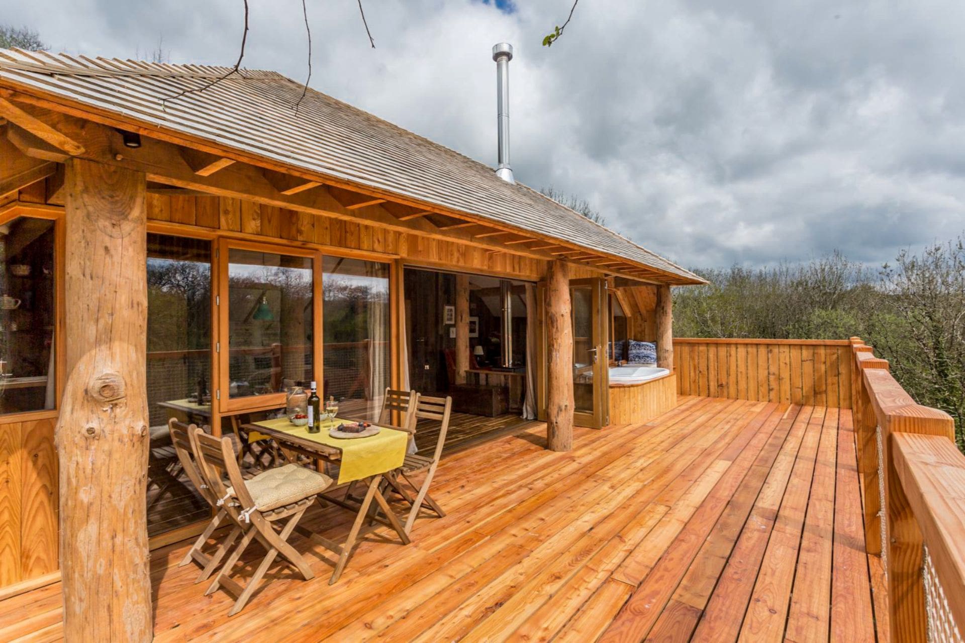 large-balcony-of-treehouse-with-a-dining-table-and-chairs-and-hot-tub-wolf-wood-treehouses-okehampton-devon-treehouse-holidays-uk-with-hot-tub