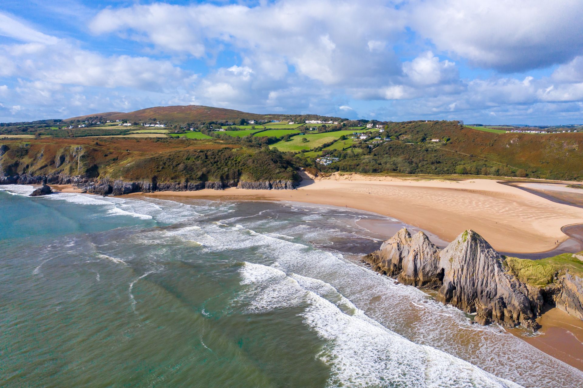 beautiful-sand-beach-with-rolling-green-fields-in-background-three-cliffs-bay-weekend-in-the-gower-swansea-bay-wales