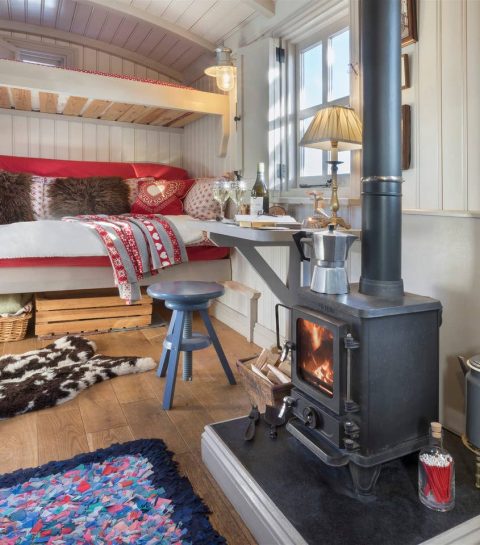 wood-stove-desk-and-sofa-bed-in-cute-shepherds-hut-lake-district-airbnb-canopy-and-stars