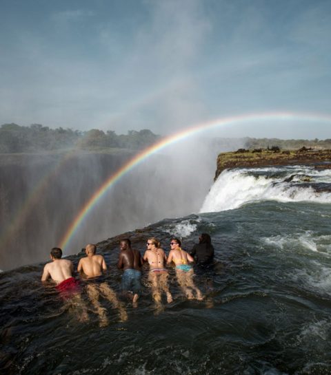 group-of-friends-lying-down-in-the-water-at-the-edge-of-victoria-falls-zambia-adrenaline-junkie-bucket-list