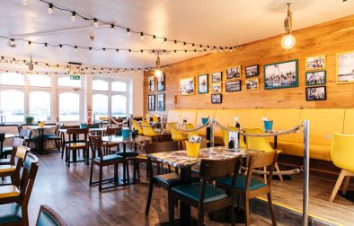 interior-of-fancy-fish-and-chip-shop-with-yellow-and-teal-tables-and-chairs-harbour-lights-places-to-eat-in-falmouth