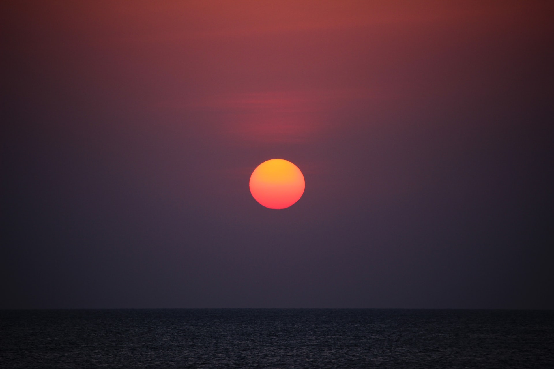 orange-sunset-over-ocean-at-night-in-dark-with-purple-skies