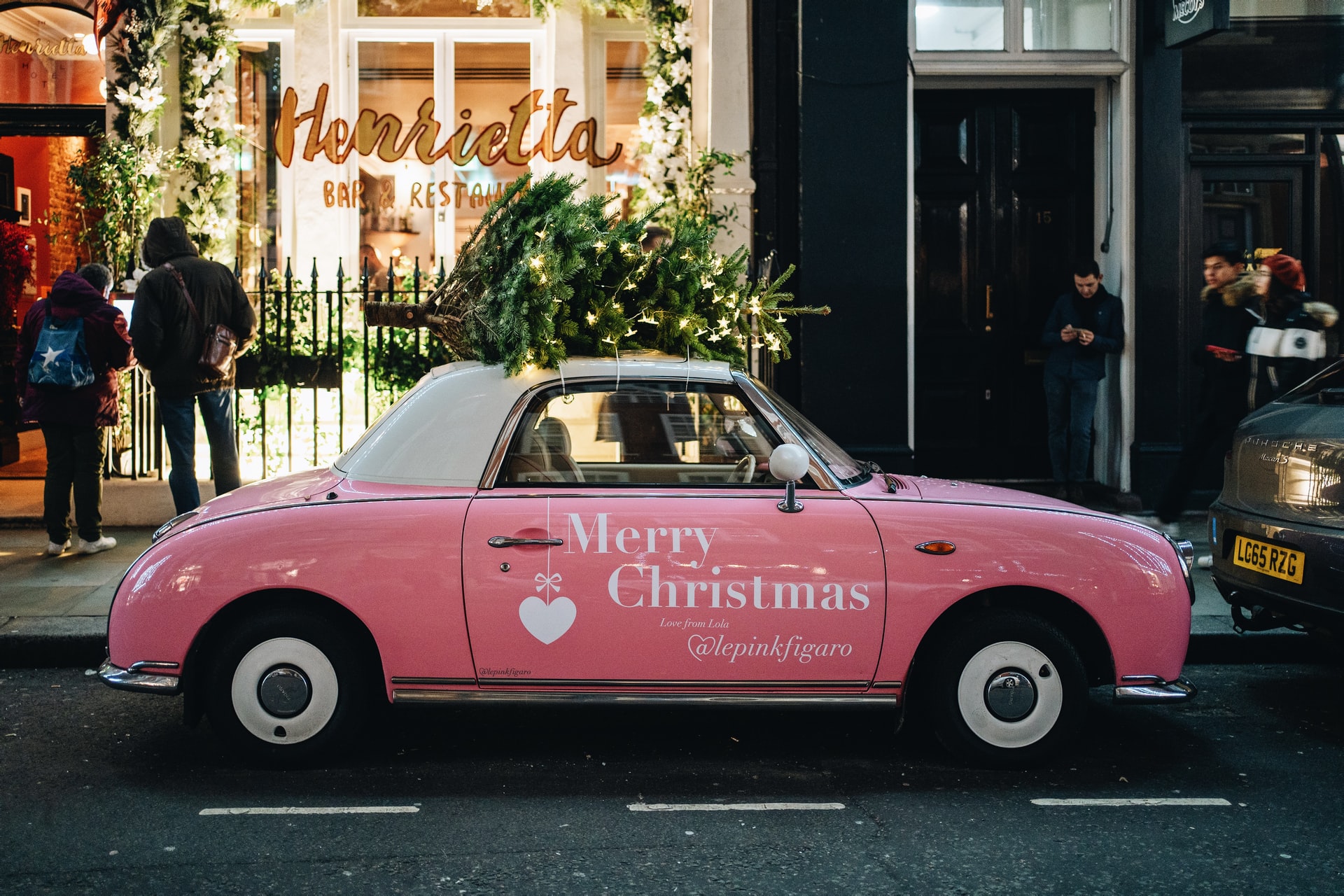 pink-car-parked-up-against-pavement-with-christmas-tree-on-top-of-it-in-covent-garden