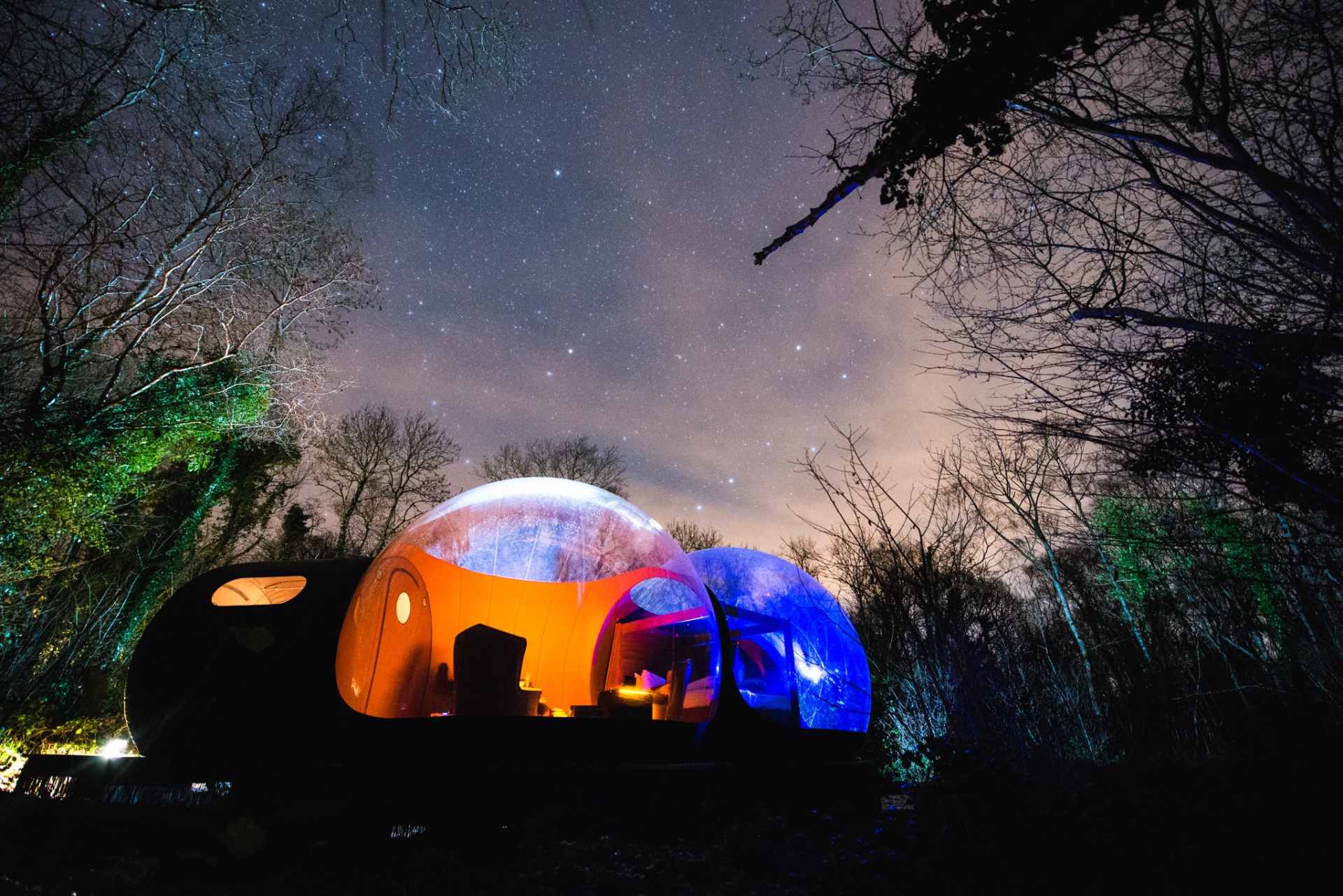 bubble-dome-lit-up-at-night-in-forest-under-stars-at-finn-lough-glamping-northern-ireland