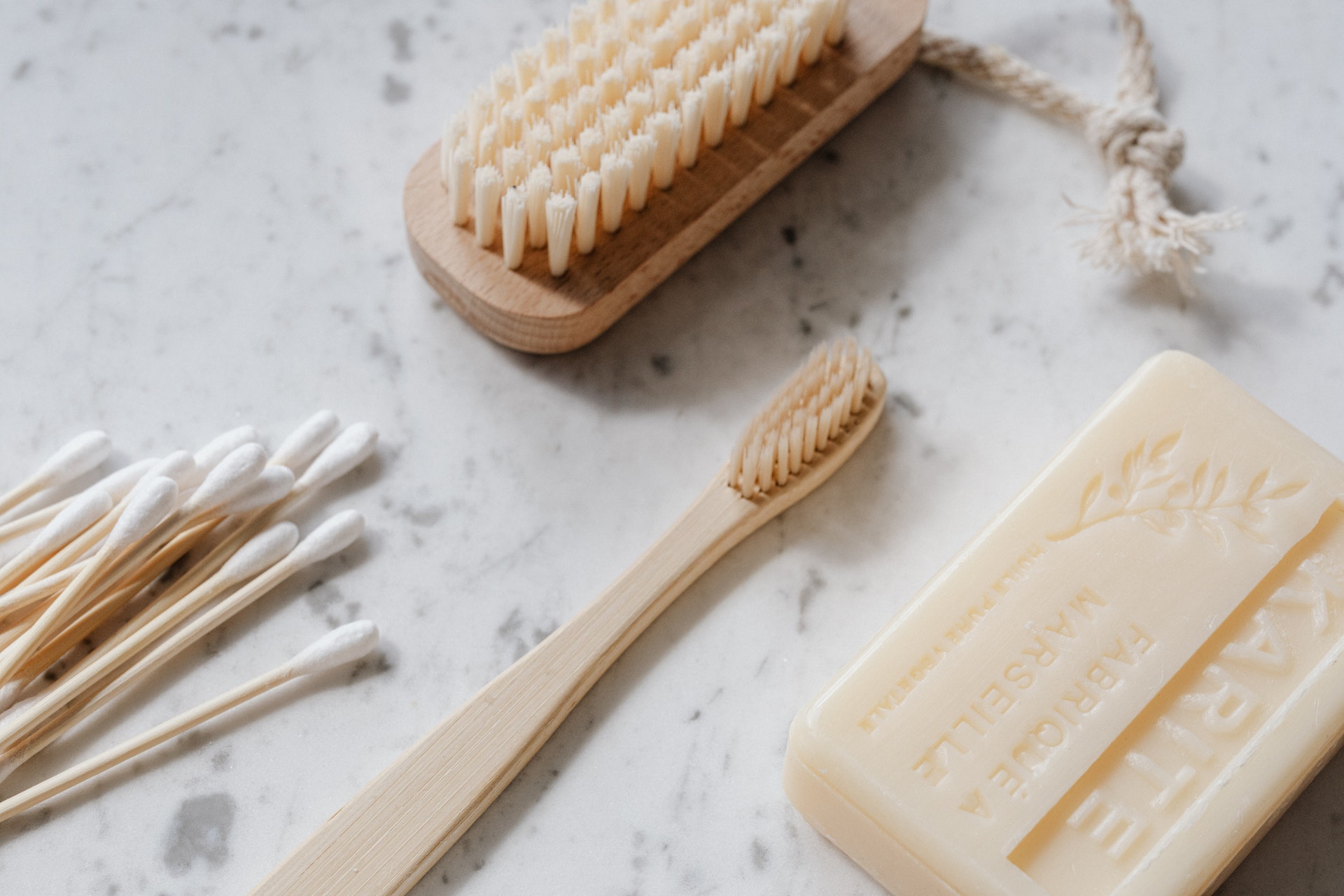 eco-friendly-bamboo-toiletries-lying-on-marble-surface-toothbrush-cotton-buds-and-bar-of-soap