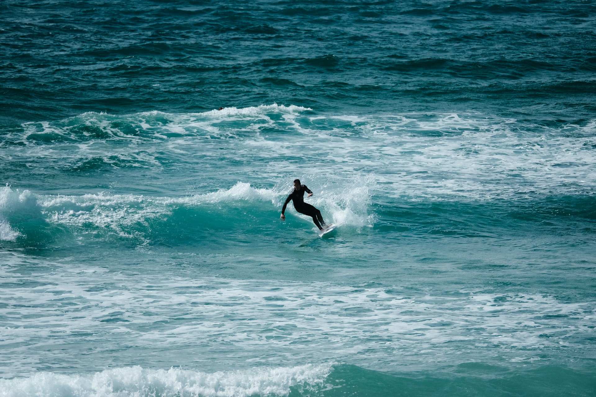 man-in-black-wetsuit-surfing-on-turquoise-sea