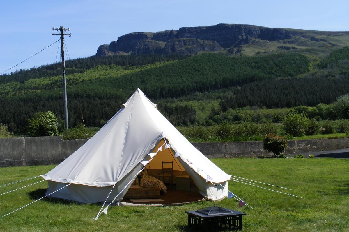 white-bell-tent-in-field-at-swanns-bridge-glamping-with-mountains-in-background