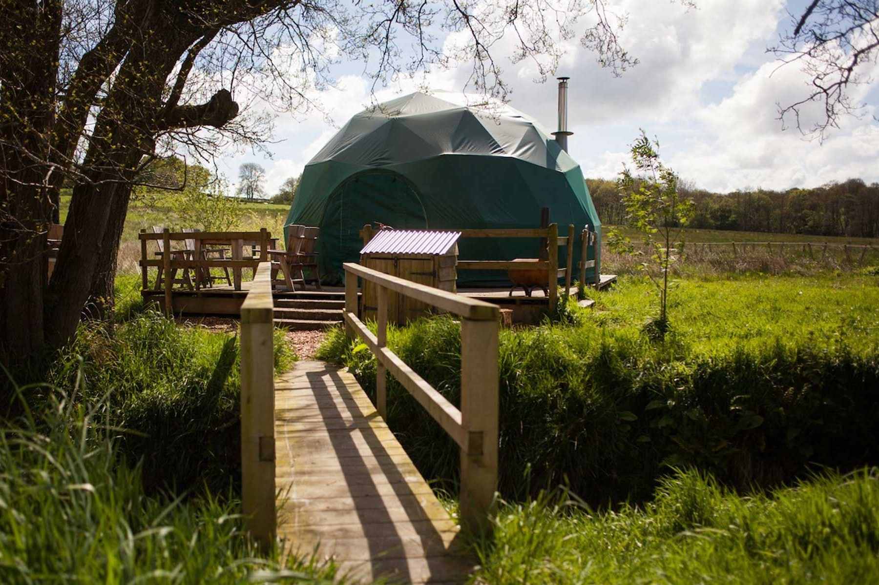 bridge-leading-to-green-glamping-geodome-in-field-at-cosy-under-canvas-glamping-herefordshire