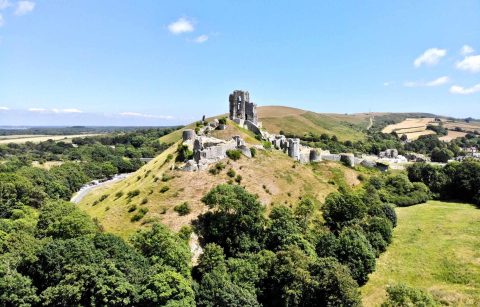 corfe-castle-sat-on-top-of-green-hill-in-summer-castles-in-dorset