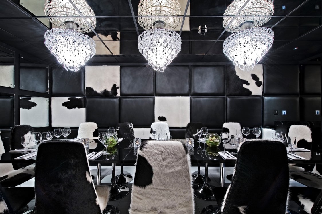dark-cow-print-room-with-a-dining-table-chairs-and-chandeliers-at-gaucho-restaurant