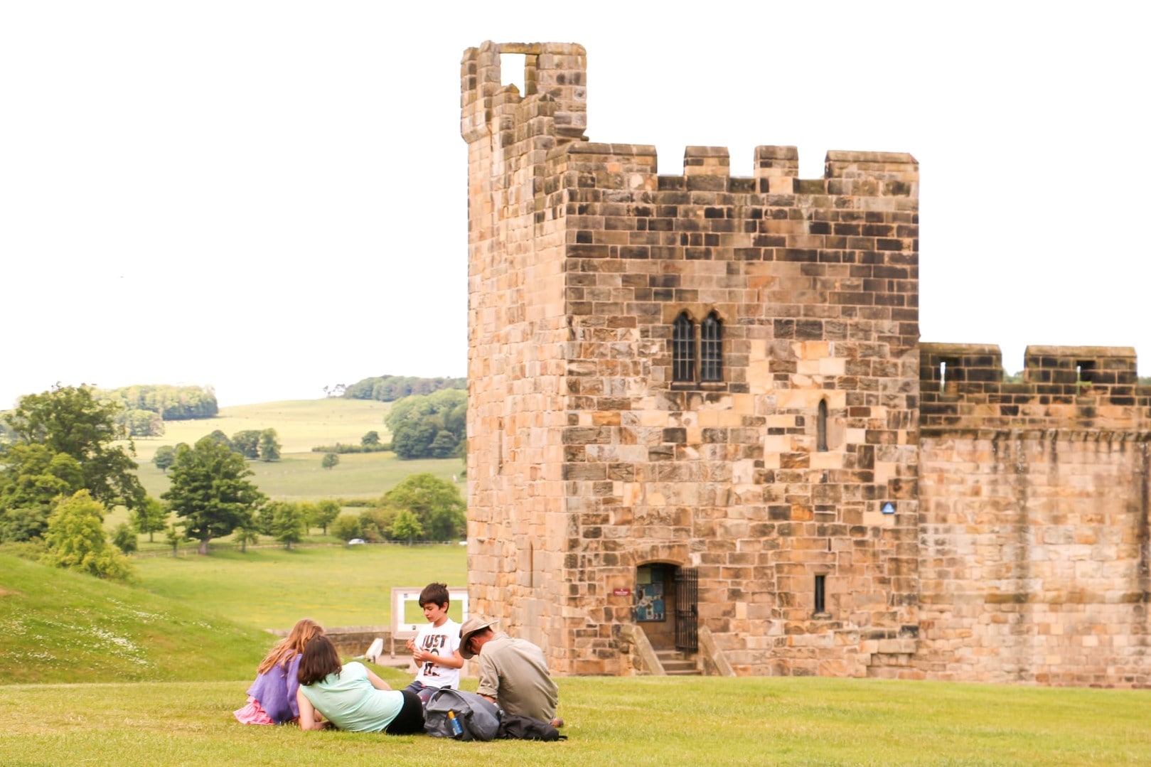 family-of-four-having-a-picnic-on-grass-by-alnwick-castle