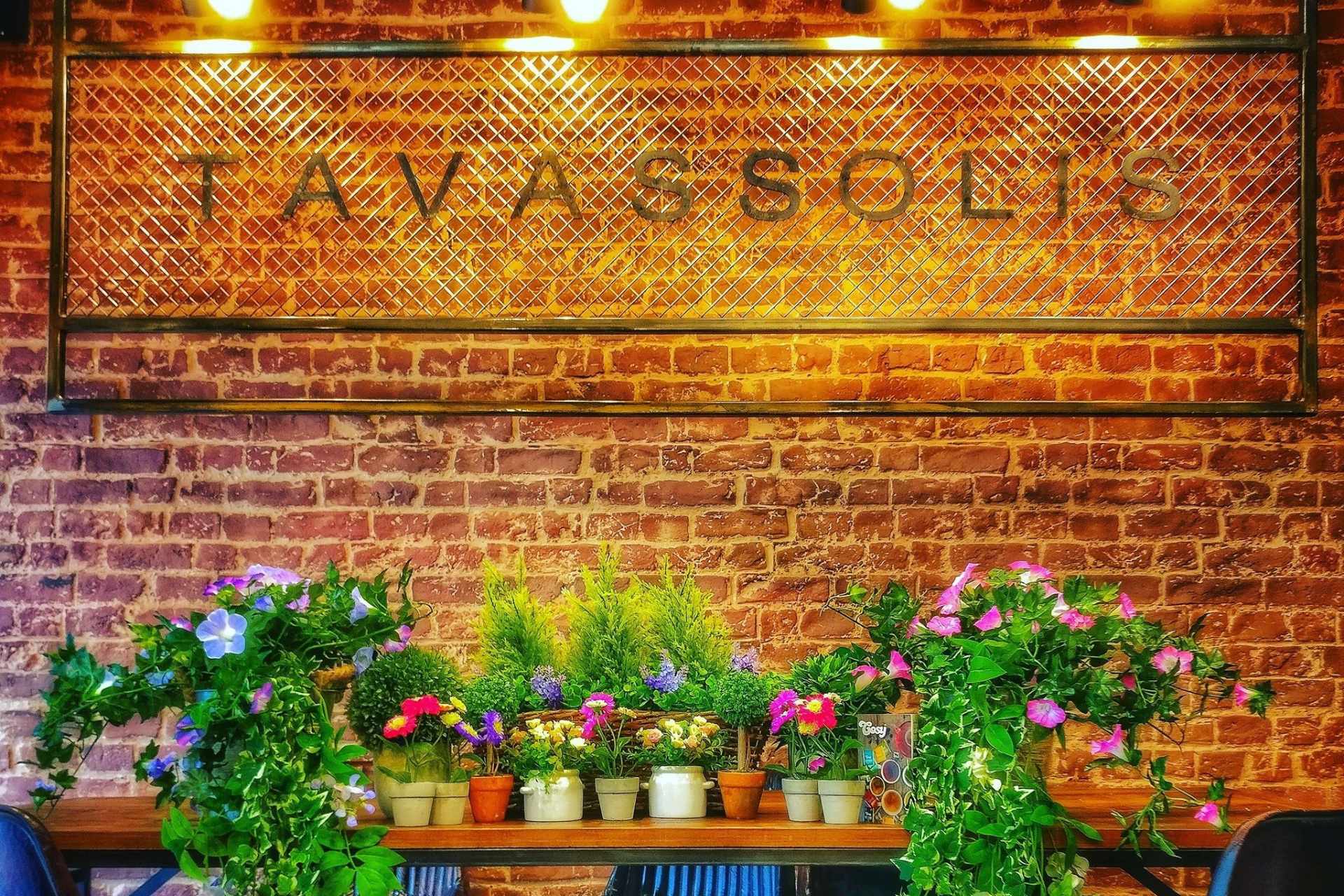 flowers-and-plants-on-table-in-front-of-brick-wall-with-tavassolis-sign