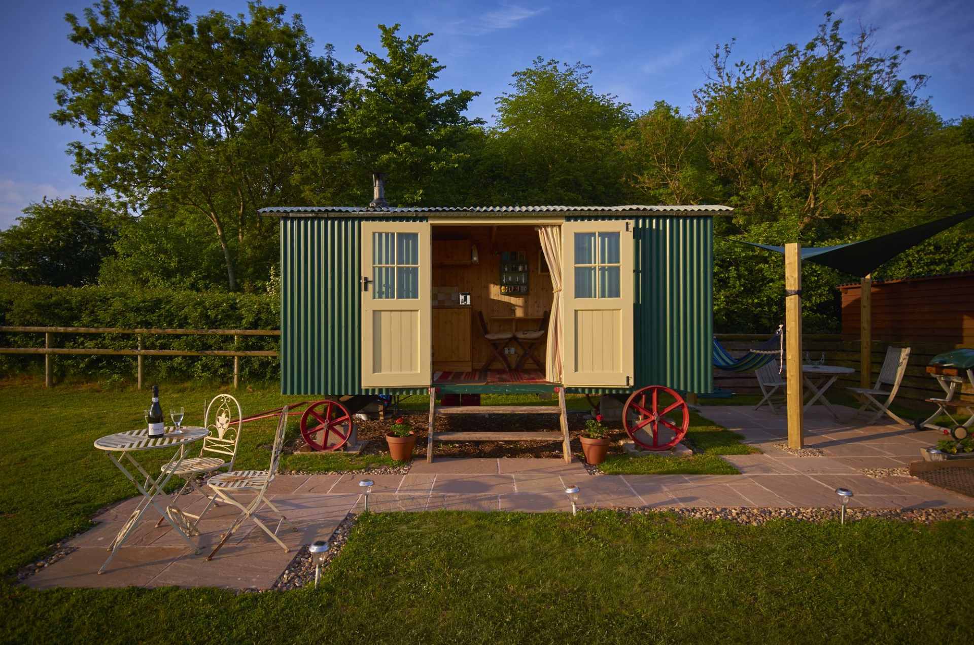 green-shepherds-hut-with-open-doors-in-field-at-upper-house-glamping