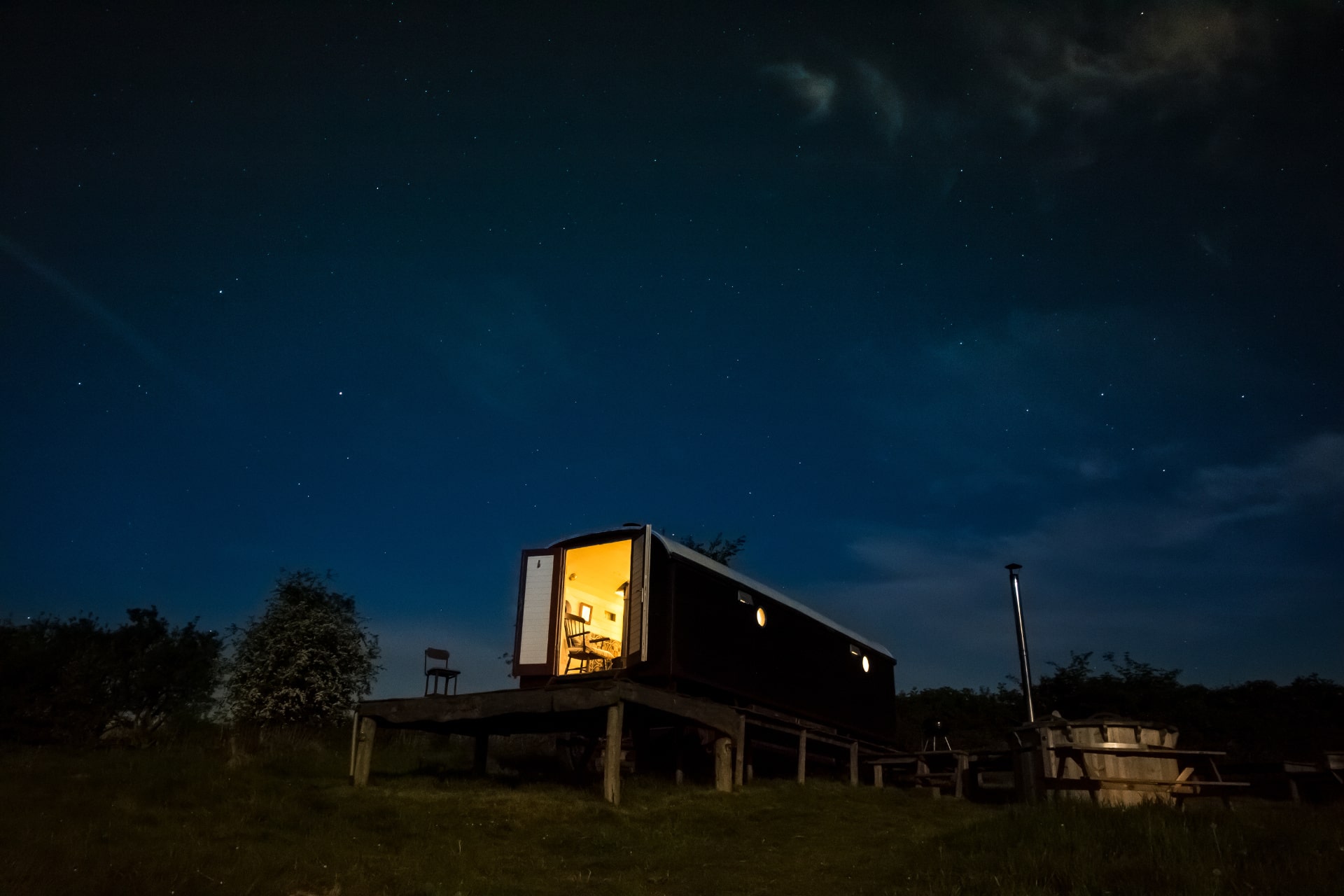 herefordshire-hideaways-stargazers-wagon-with-hot-tub-lit-up-at-night-under-a-starry-night-sky-glamping-herefordshire