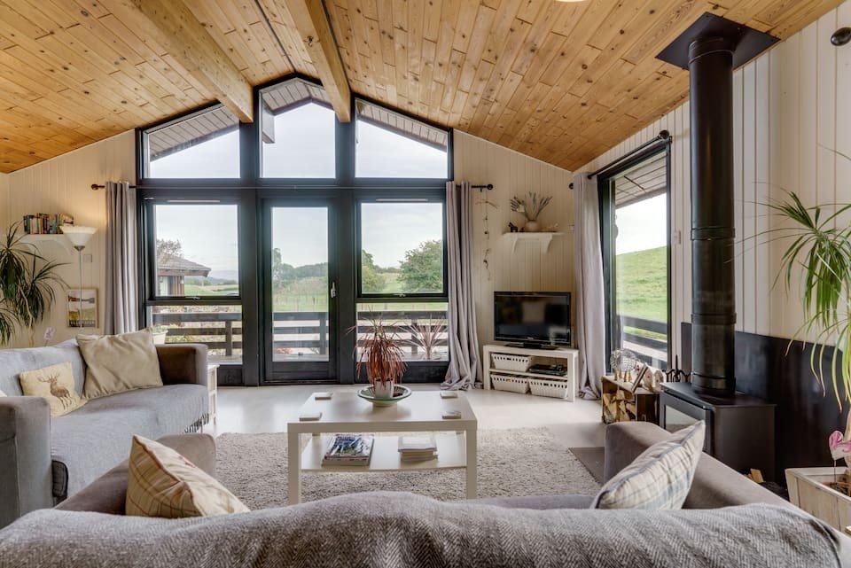 living-area-with-fire-and-sofas-and-large-windows-in-herdyview-lodge-in-yanworth-near-ullswater-airbnbs-lake-district
