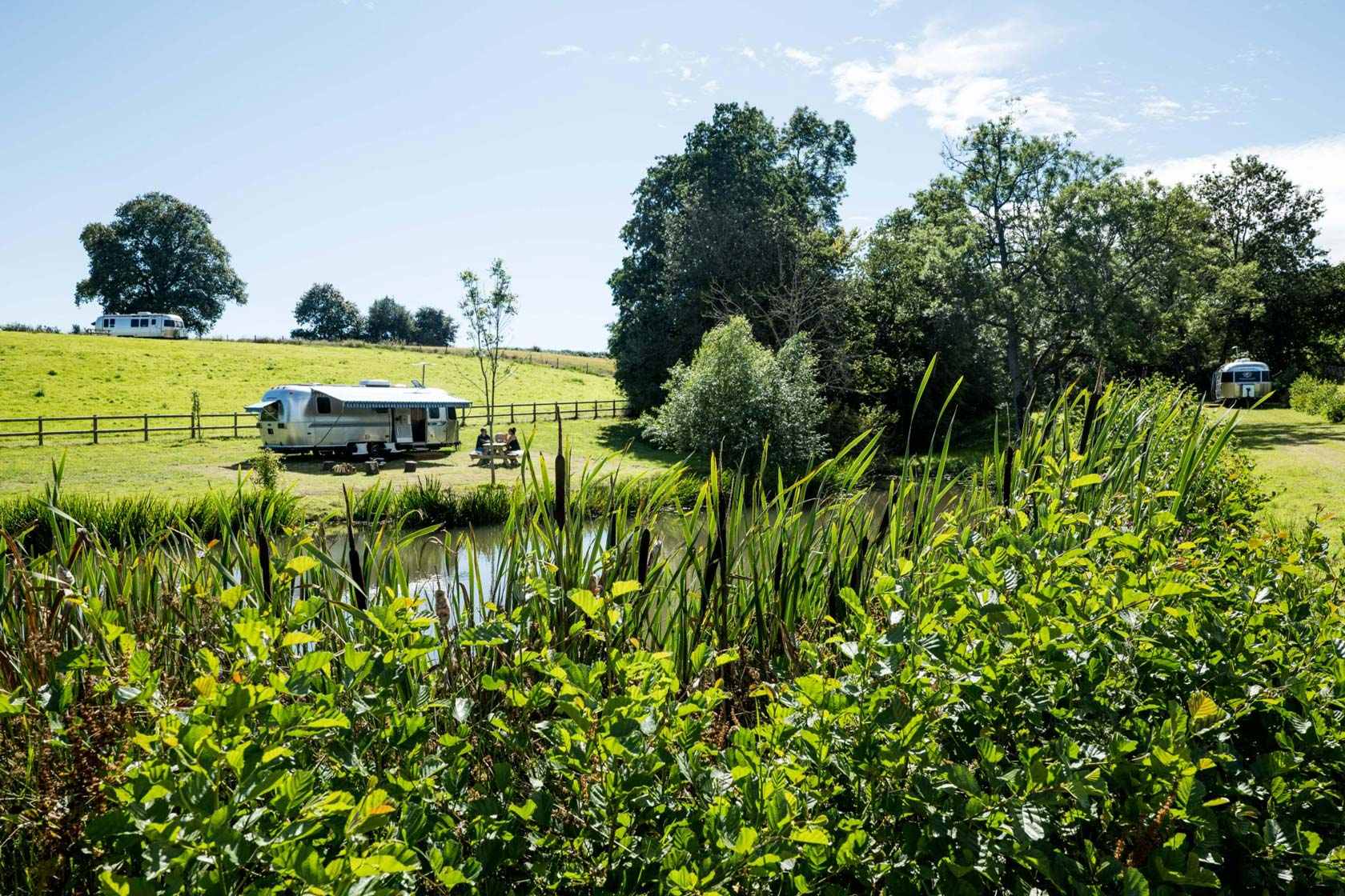 silver-airstream-by-large-lake-on-sunny-day-at-the-wells-glamping-herefordshire