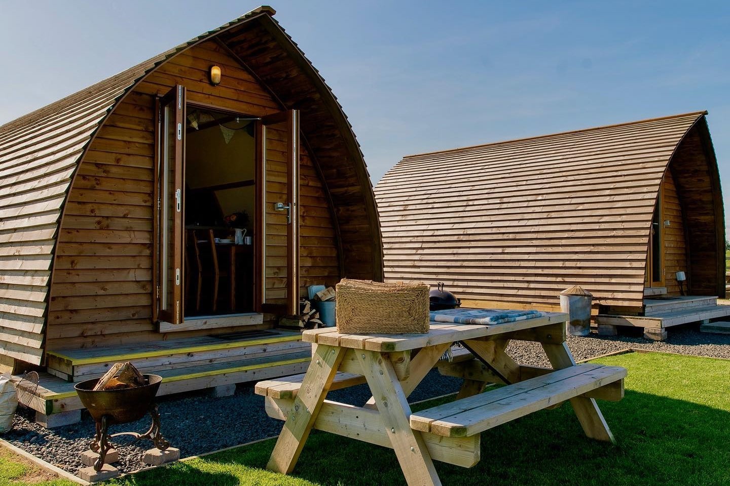 two-glamping-pods-in-field-with-a-picnic-table-at-springhill-farm-wigwams