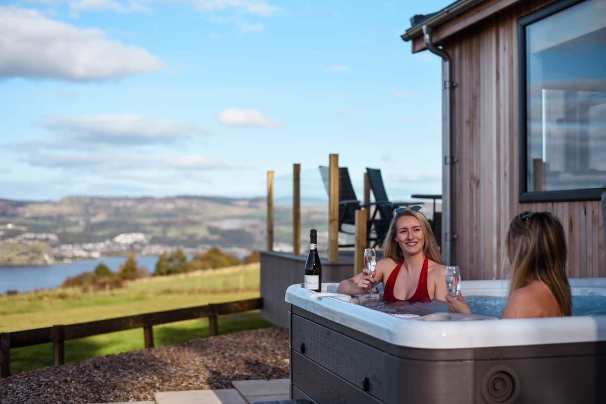 two-young-woman-in-hot-tub-by-pheasant-lodge-in-countryside