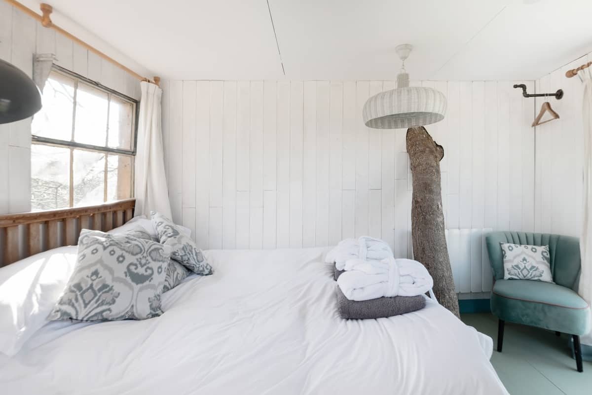 white-bedroom-with-tree-going-through-wall-in-treehouse