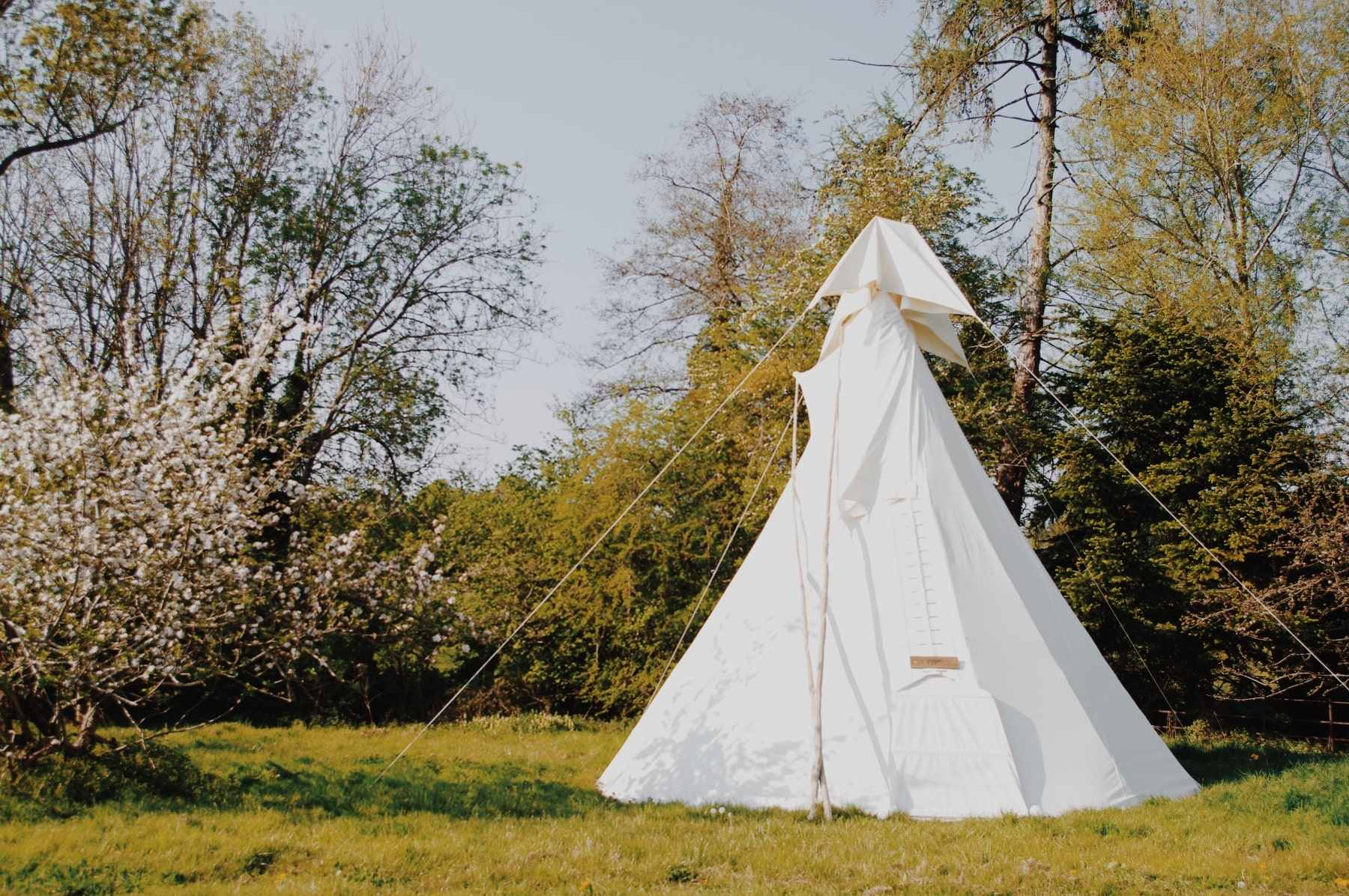 white-bell-tent-in-field-in-spring-at-white-house-glamping