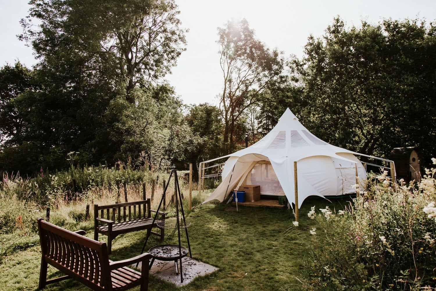 white-moat-island-stargazer-bell-tent-in-field-with-two-benches-and-firepit-glamping-norfolk