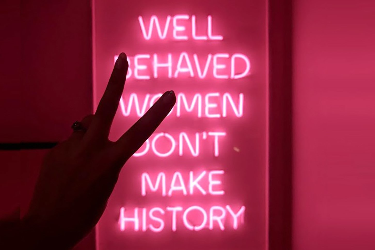 women-throwing-a-piece-sign-in-front-of-neon-pink-well-behaved-women-sign-at-tonight-josephine