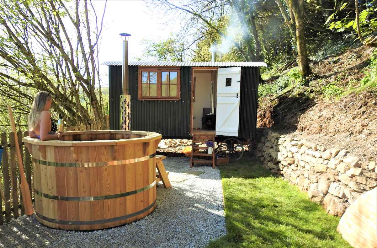 blonde-woman-in-woodfired-hot-tub-by-eileen-shepherds-hut-glamping-with-hot-tub-cornwall