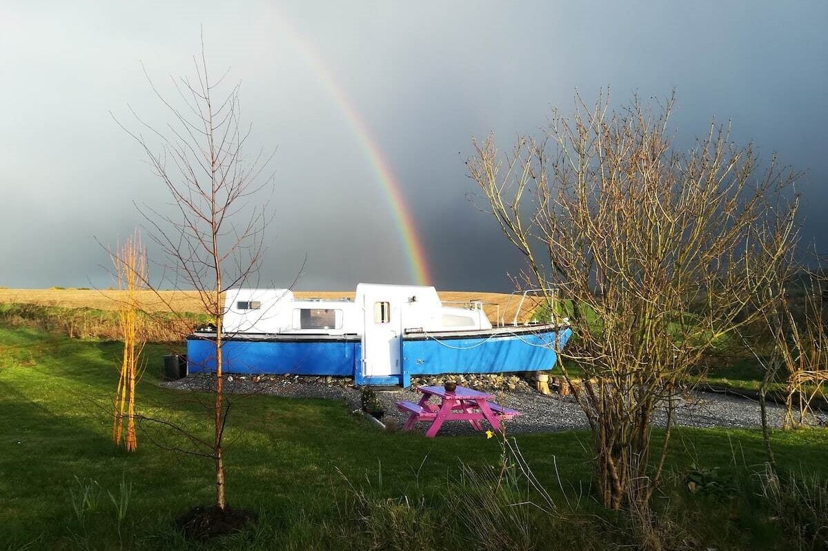 blue-and-white-land-boat-in-field-with-rainbow-in-sky