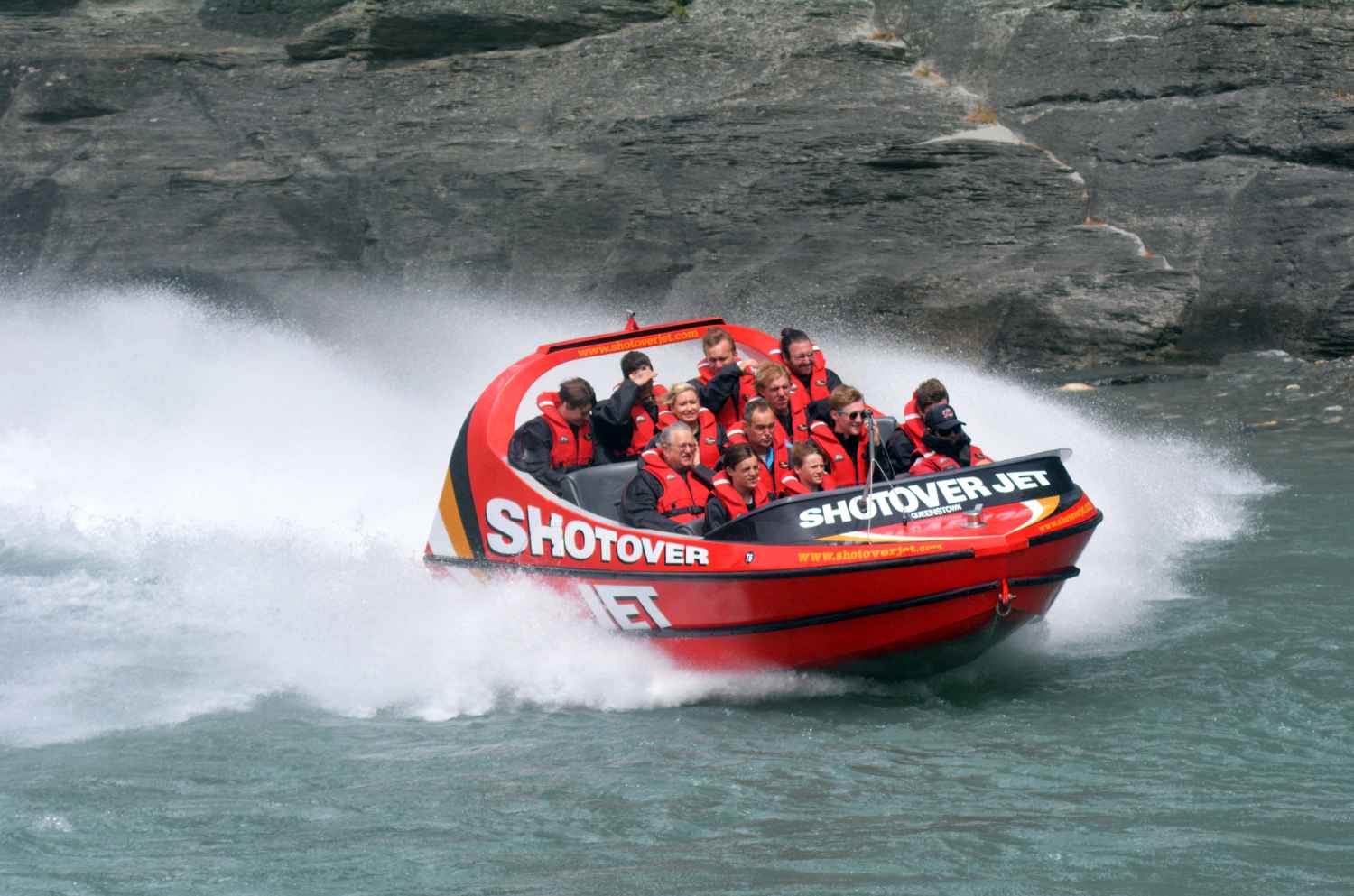 people-on-red-shotover-jet-boat-going-down-river