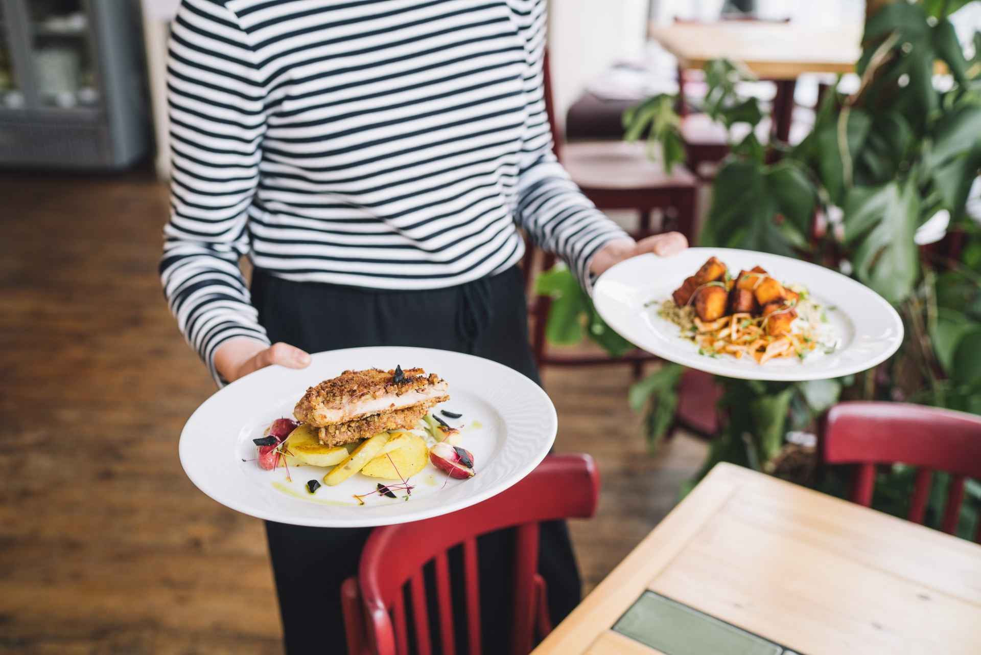 waitress-serving-two-plates-of-food-at-eat-your-greens-vegan-restaurants-leeds