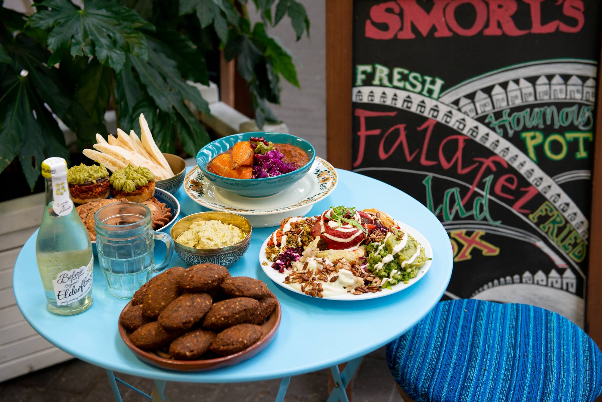 plates-and-bowls-of-food-on-round-blue-table-at-smorls-best-vegan-restaurants-brighton
