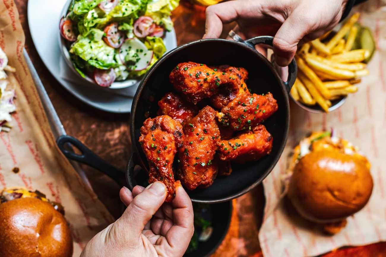 hands-holding-bowl-of-chicken-wings-at-the-blues-kitchen
