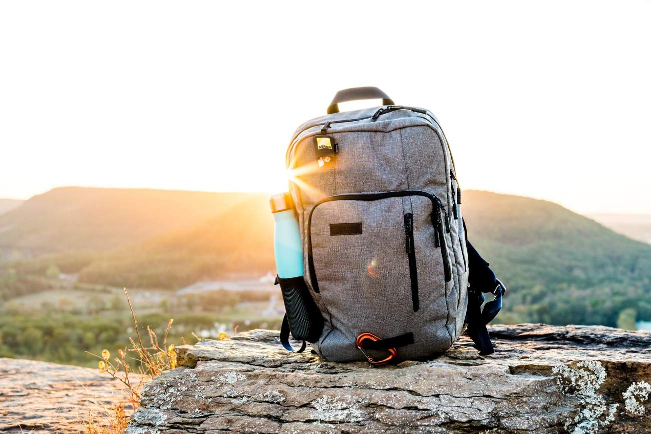 backpack-and-water-bottle-on-rock-on-mountain-road-trip-packing-list
