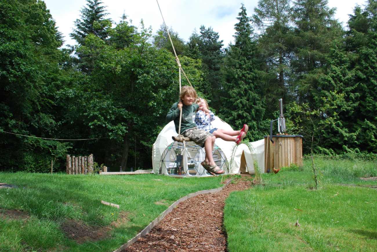 kids-swinging-in-front-of-geodome-at-the-dome-garden