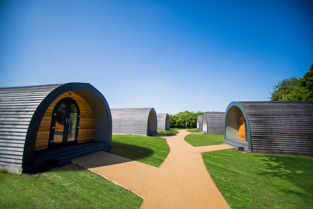 six-larch-clad-glamping-pods-in-field-on-sunny-day-glamping-gloucestershire