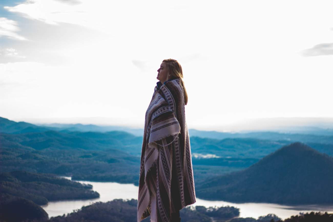 woman-wrapped-in-blanket-at-sunset-on-mountain