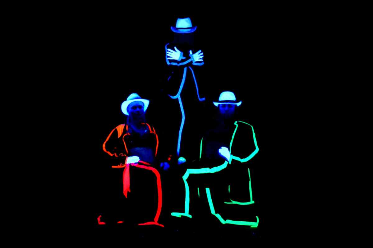 three-people-lit-up-in-darkness-at-black-light-theatre