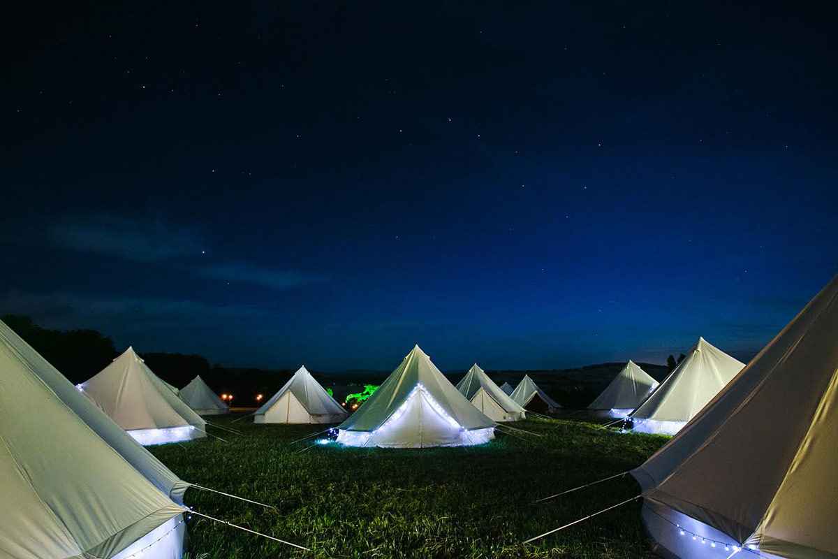 purbeck-glamping-bell-tents-lit-up-in-field-at-night