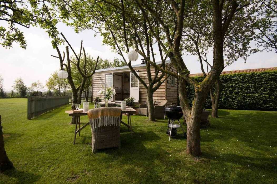 secluded-shepherds-hut-with-outdoor-table-and-chairs-in-field