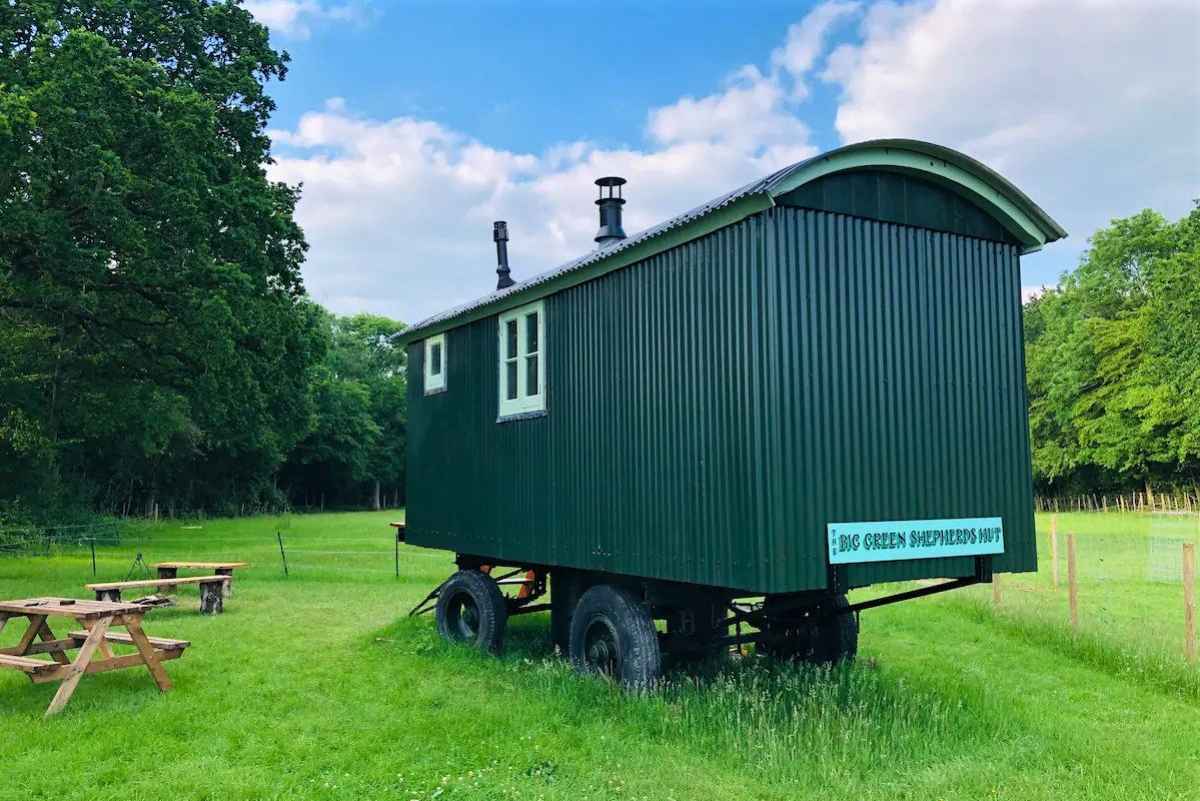 the-big-green-shepherds-hut-with-picnic-tables-in-field