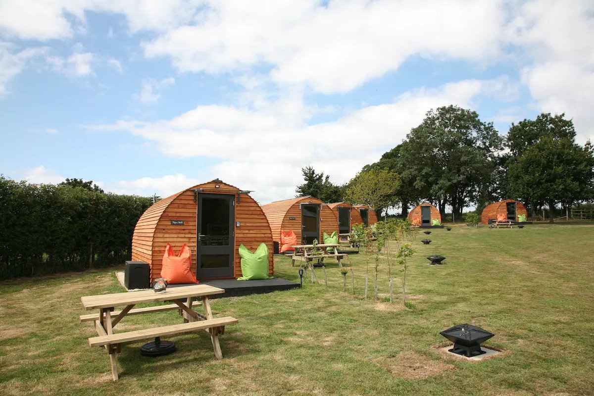 the-paddocks-glamping-pods-with-picnic-tables-in-field