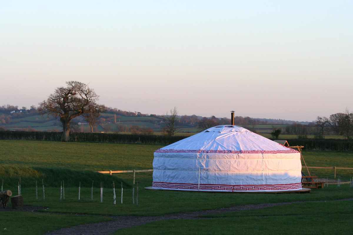 white-caalm-camp-yurt-in-field-at-sunset