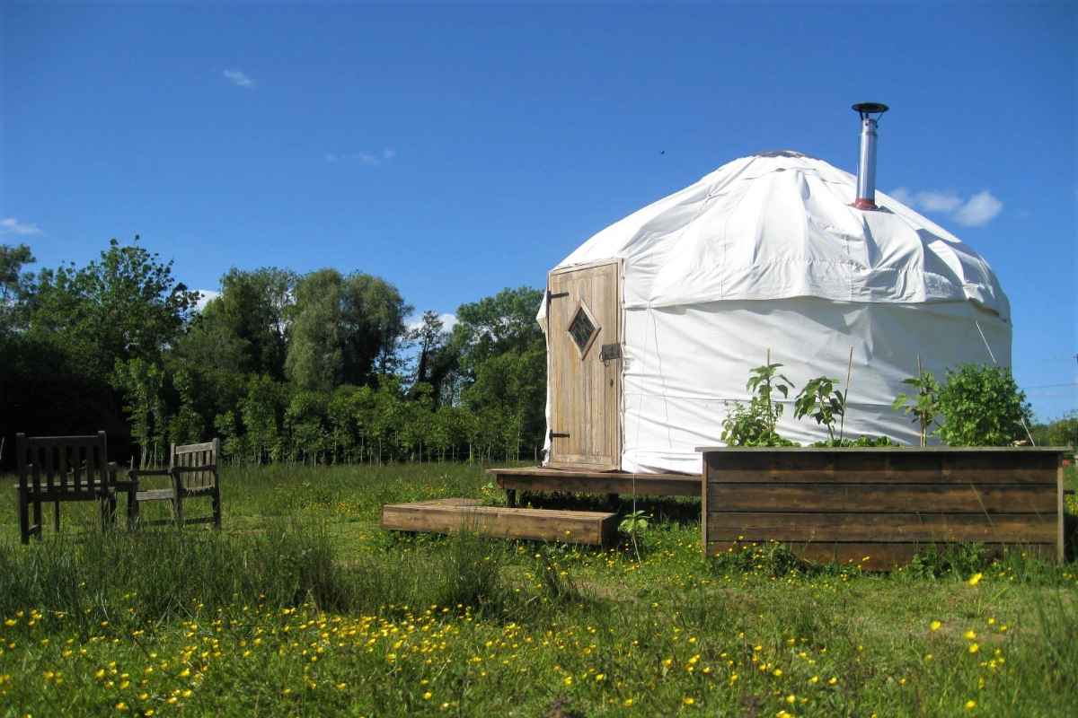 white-mountain-cottage-yurt-on-decking-in-field-on-sunny-day
