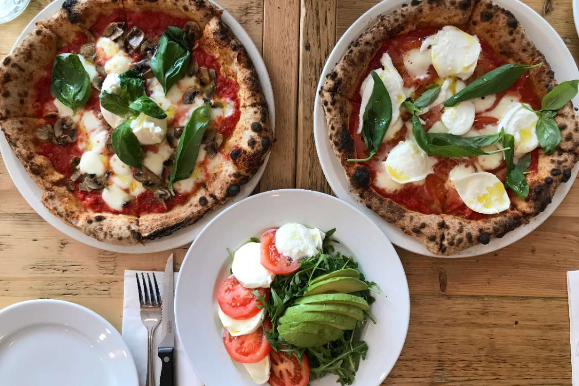 zia-lucia-two-pizzas-and-salad-on-table